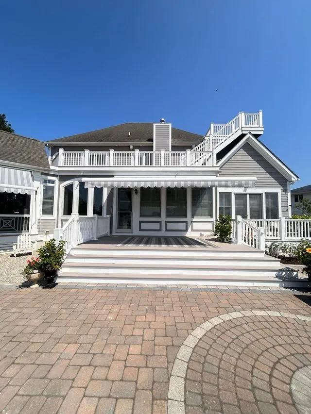 Coastal home with gray shingle roof and white gutters in the fall